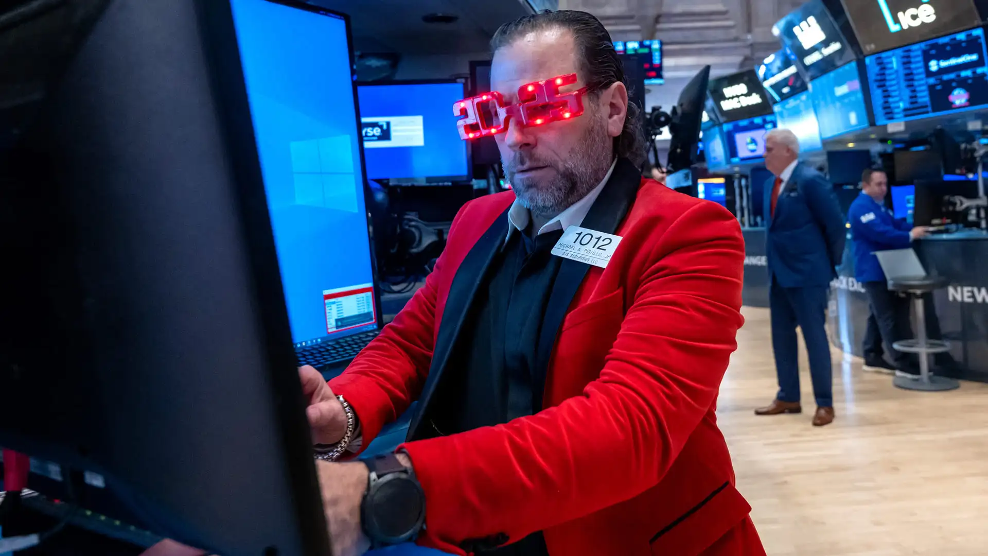 Stock trader wearing red jacket and "2025" shaped red glasses.