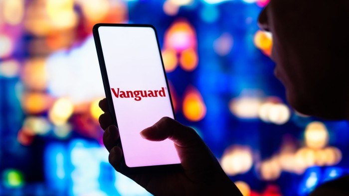 A phone showing the Vanguard logo is held up